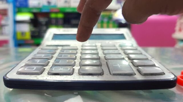Close-up of a person using a calculator in a shop for financial business calculations