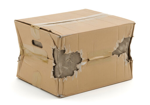 Damaged brown cardboard shipping box with torn sides and crushed corners, isolated on a white background, showing signs of rough handling