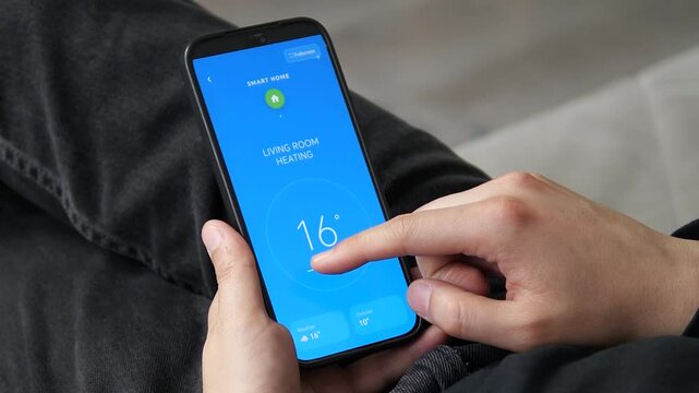 Mobile interface for smart home heating with real-time indoor and outdoor temperature display. User adjusts from warm to cool setting. Ideal for videos about IoT devices, climate control, and efficien