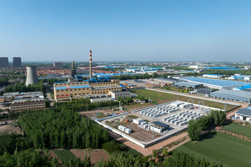 Obraz premium Aerial view of industrial park featuring cooling tower smokestack and factory buildings