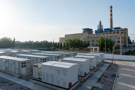 Energy storage station with battery cabinet arrays and industrial factory building in background