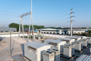 Fototapeta premium Outdoor substation with power equipment transmission towers and high voltage lines under clear blue sky