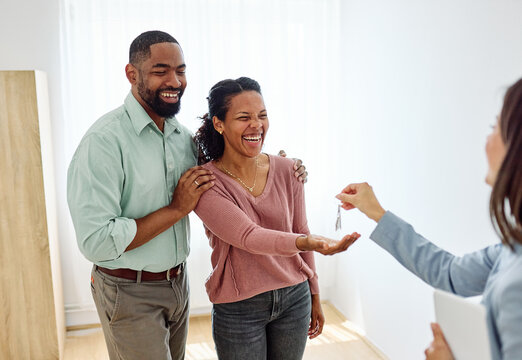 Young black couple receiving keys of new apartment from their real estate agent, standing in the new home