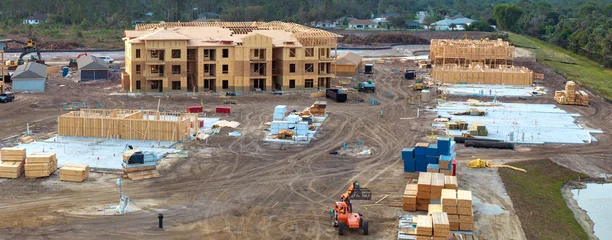 Unfinished frames of apartment condos with wooden roofs under construction. Development of residential housing in US suburbs. Real estate market in the USA © bilanol