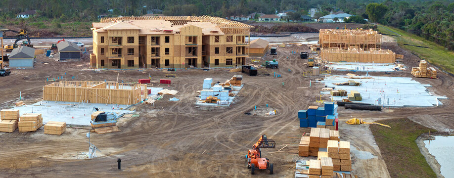 Unfinished frames of apartment condos with wooden roofs under construction. Development of residential housing in US suburbs. Real estate market in the USA