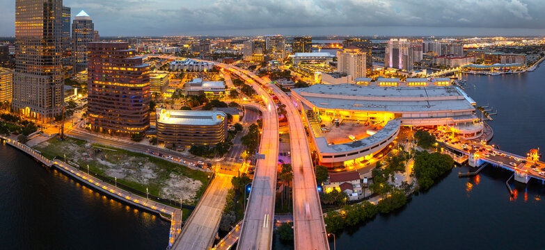 Night urban landscape of downtown district of Tampa in Florida, USA. American city skyline with brightly illuminated high commercial buildings and bridge over Hillsborough river.