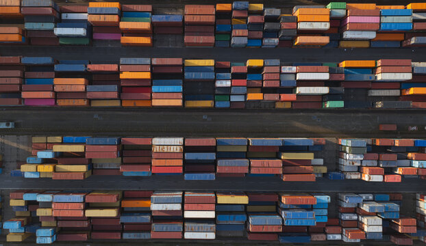 Portugal - 25 June 2026: Aerial view of shipping containers arranged in rows at a container terminal in a port, with vibrant colors and geometric patterns visible from above.