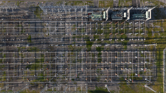 Portugal - 25 June 2026: Aerial view of an electricity power plant with high-voltage transmission lines, electrical transformers, and metal structures casting long shadows.