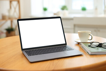 Fototapeta premium Comfortable home workplace with laptop on wooden table in kitchen, closeup