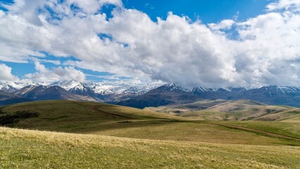 Fototapeta premium Dzhily-Su, Russia - June 4, 2026: View of the Caucasus Mountains along the road to Dzhily-Su, showing mountain peaks, valleys, winding road, open landscapes, and scenic natural surroundings.