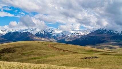 Fototapeta premium Dzhily-Su, Russia - June 4, 2026: View of the Caucasus Mountains along the road to Dzhily-Su, showing mountain peaks, valleys, winding road, open landscapes, and scenic natural surroundings.