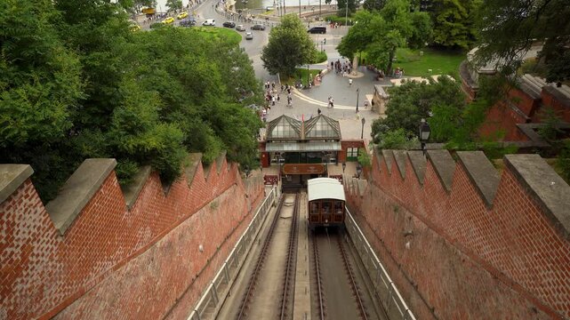 video of Budapest's Castle Hill funicular railway ascending through brick tunnel walls with city plaza and traffic visible above, showcasing historic transportation and urban landscape.