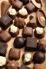 Naklejka premium Delicious chocolate candies on wooden table, above view