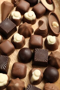 Delicious chocolate candies on wooden table, above view