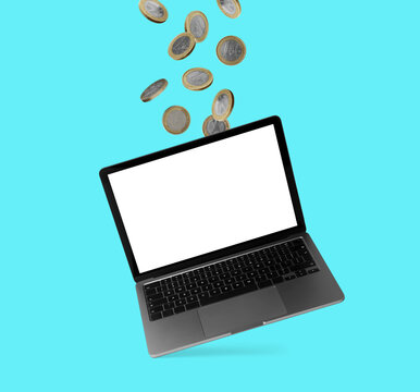 Coins flying into laptop on turquoise background. Online payment
