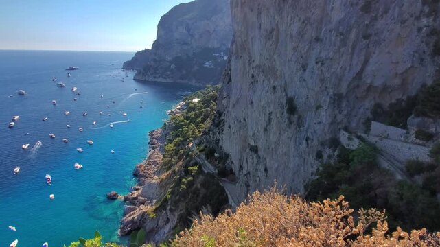 Beautiful high angle view of the rocky coastline and blue sea with boats as seen from the historic Gardens of Augustus in Capri Italy