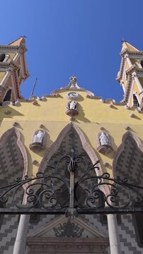 Beautiful low angle view of the ornate yellow facade and twin steeples of the Cathedral Basilica of the Immaculate Conception in the historic center of Mazatlan Mexico
