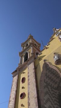 Beautiful low angle view of the ornate yellow facade and twin steeples of the Cathedral Basilica of the Immaculate Conception in the historic center of Mazatlan Mexico