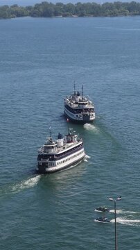 Scenic high angle view of two traditional passenger ferries sailing across the blue water of Toronto Harbour toward Toronto Island