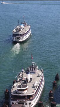 Scenic high angle view of two traditional passenger ferries sailing across the blue water of Toronto Harbour toward Toronto Island
