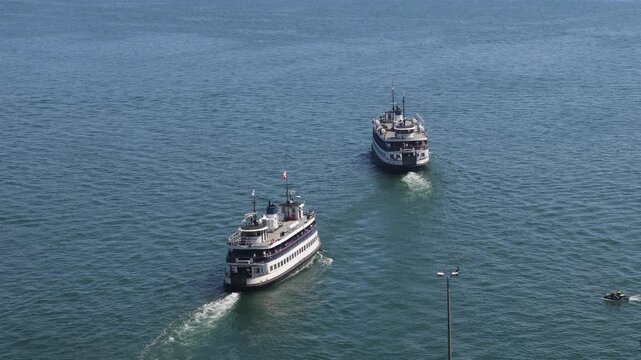 Scenic high angle view of two traditional passenger ferries sailing across the blue water of Toronto Harbour toward Toronto Island