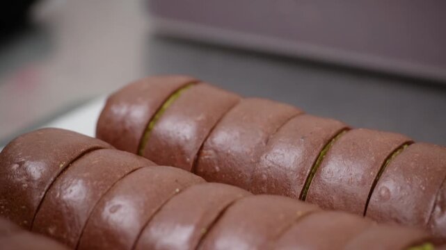 A close-up, high-angle shot of a soft chocolate-flavored pastry roll, sliced to showcase a thick, creamy matcha green tea custard filling. The contrast between the dark cocoa exterior and the bright g