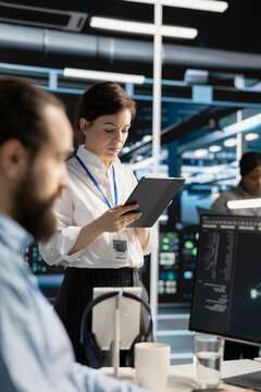Data center engineer uses a digital tablet in a data center to manage AI virtualization and optimize server infrastructure.