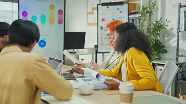 Diverse multiracial team presenting AI-powered marketing restructuring strategy on screen in modern open office, analysts reviewing business documents and data for corporate transformation concept