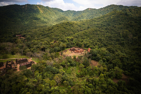 Aerial view of the historic brick ruins of My Son Sanctuary nestled within a lush green jungle landscape in the mountains Thu Bon, Da Nang, Vietnam.