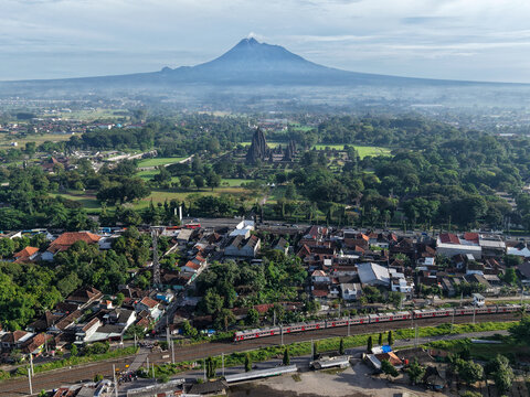 Aerial view of Prambanan Temple with Mount Merapi in the background and a train passing through the village, Prambanan, Daerah Istimewa Yogyakarta, Indonesia.