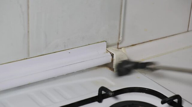 Cleaning dirt and grime from kitchen corners and appliances while using a brush steam cleaner