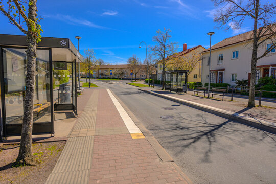 Gothenburg, Sweden - May 06 2026: Quiet suburban bus stop beside empty street under blue sky.