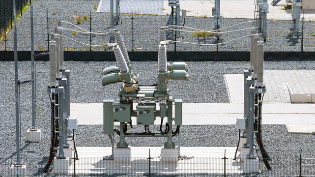 Aerial view of electrical substation equipment featuring high voltage circuit breakers and insulators installed on a gravel ground surface in Espel, Flevoland, Netherlands.