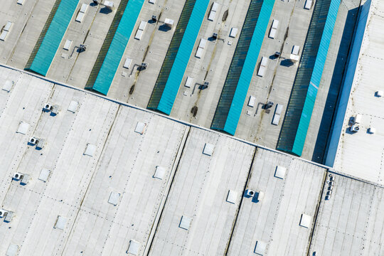 Aerial view of the industrial area with large grey rooftops and rows of teal skylights in Prague, Prague, Czechia.