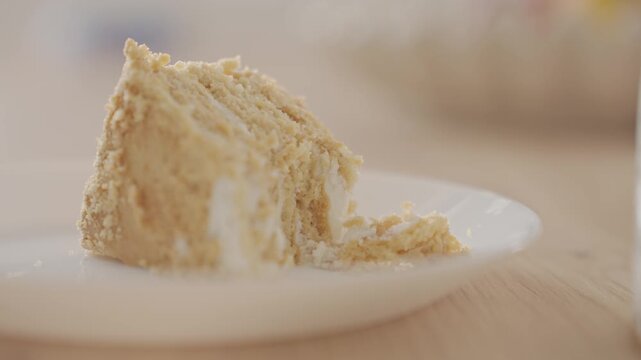 Fork breaks off a piece of layered cake with cream on plate. Concept of homemade dessert and sweet food serving