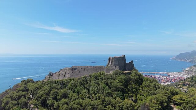 Aerial view of Castello di Arechi medieval fortress on forested hilltop with Salerno commercial port, marina, container terminal, and vast Gulf of Salerno panorama, Italy