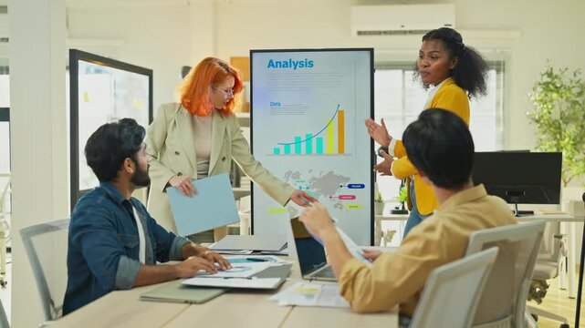 Diverse multiracial team presenting AI-powered marketing restructuring strategy on screen in modern open office, analysts reviewing business documents and data for corporate transformation concept