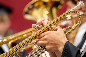 Musician's hands press the valves of a brass trumpet during a live concert band performance. A picture of music education, practice, and the focus it takes to play a wind instrument on stage. © Jeanne Sager Photo
