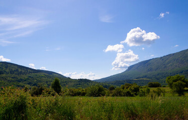 Obraz premium Lush Green Mountain Slopes Under Majestic Blue Sky with Clouds