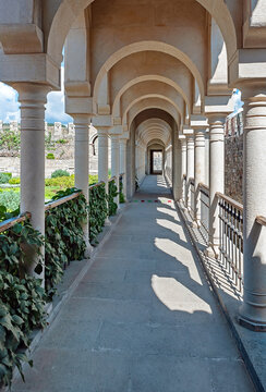Passageway with white columns in the courtyard of Akhaltsikhe (Rabati) Castle, overgrown by green plants, Georgia