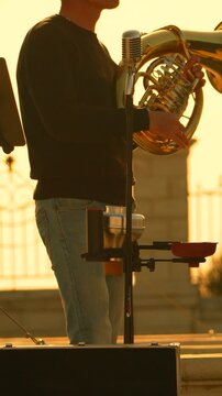 Musician tuba sunset playing brass instrument outdoors during golden hour performance with vintage microphone and warm lighting atmosphere