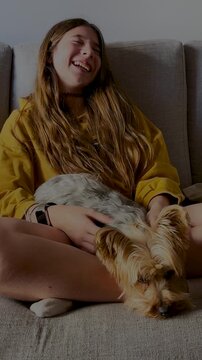 Blonde girl playing and laughing with her puppy at home. 4K vertical recording.Teenager enjoying a cute moment with her puppy at home. Free lifestyle concepts.Ideal format for social media stories.