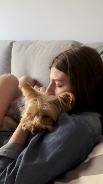 A relaxed blonde girl is enjoying time with her yorkie. Free lifestyle concept. Moments of serenity and felicity. Looking after nice pets.