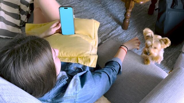 Young blond girl having relaxing time on a sunny morning in her livingroom. Free lifestyle concept. Moments of calm and happiness. Teenagers relax and technology.