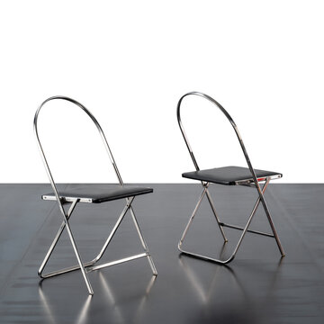 pair of folding chairs, featuring a chromed metal frame and black leather seat.