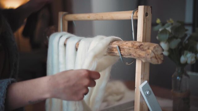 Young artisan woman arranging wool roving to begin a decorative tapestry, showcasing handmade textile art, craftsmanship and the creative process.
