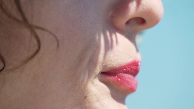 Woman eating dessert close up of female enjoying a vanilla ice cream cone against the blue sky on summer day