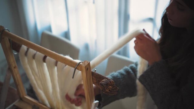 Young artisan woman working with wool roving, showcasing handmade textile art, fiber craftsmanship and the creative process in a craft studio.
