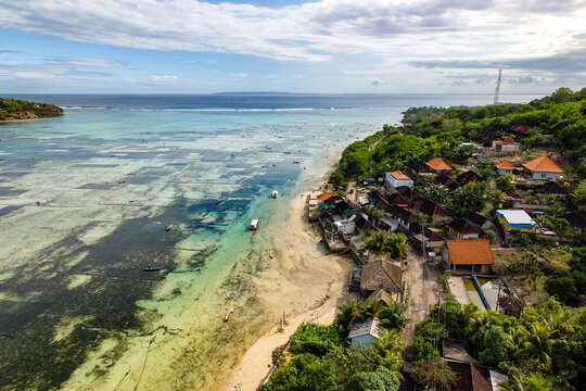 Scenic view of sandy beach, boats, and seaweed farming grids in Nusa Lembongan, Bali