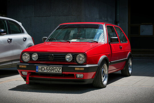 Front corner view of a vintage red Volkswagen Golf Mk2 GL hatchback (Typ 19E, A2 platform) in custom tuned condition with four headlights, parked on a street in Subotica, Serbia, June 7, 2026